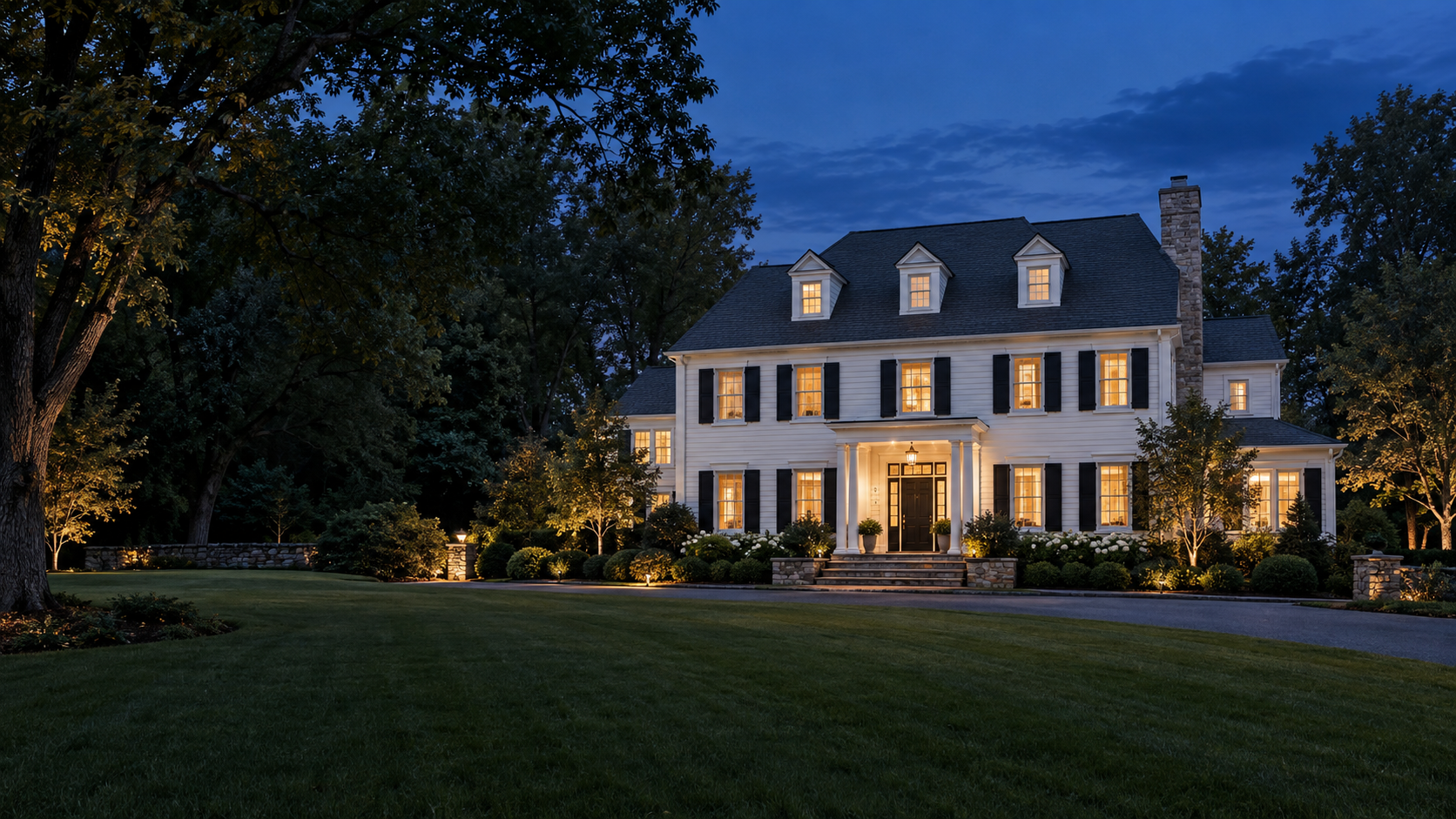 Illustrative colonial-style home with warm windows at dusk; not a property for sale